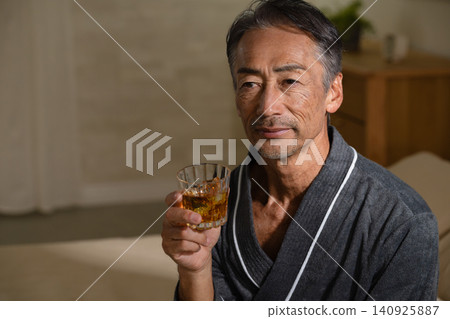 Senior man wearing a gown and holding a rocks glass Lifestyle image Senior man wearing a gown and holding a rocks glass Lifestyle image 140925887