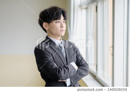 A young businessman with his arms crossed by the window. A young businessman with his arms crossed by the window. 140926039