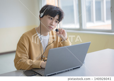 A young man on a headset answers the phone. A young man on a headset answers the phone. 140926041