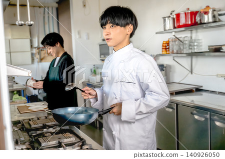 一位年輕廚師在廚房做飯 一位年輕廚師在廚房做飯 140926050