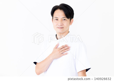 一位身穿白大褂的中年男性針灸師/整骨師,一隻手放在胸前。 一位身穿白大褂的中年男性針灸師/整骨師,一隻手放在胸前。 140926632