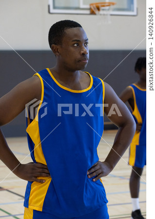 African American male team standing hands-on-hips at center court in blue yellow jerseys near hoop African American male team standing hands-on-hips at center court in blue yellow jerseys near hoop 140926844