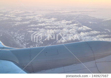 Aerial View of Snow-Capped Mountains at Sunset from Airplane Window 140927087