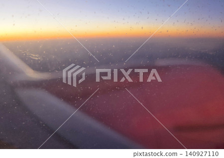 Sunrise over the horizon viewed from an airplane window while flying at high altitude during early morning hours Sunrise over the horizon viewed from an airplane window while flying at high altitude during early morning hours 140927110
