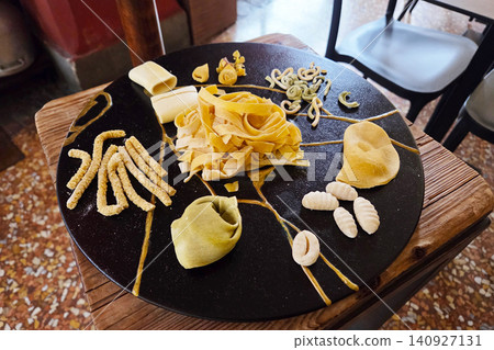 Unique pasta presentation on a black plate at a restaurant in Italy during lunch with various shapes and colors Unique pasta presentation on a black plate at a restaurant in Italy during lunch with various shapes and colors 140927131