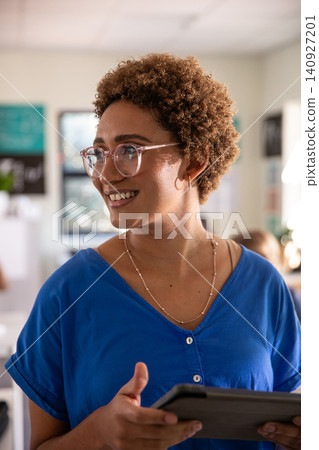 African American woman wearing eyeglasses holding tablet standing in classroom with poster charts African American woman wearing eyeglasses holding tablet standing in classroom with poster charts 140927201