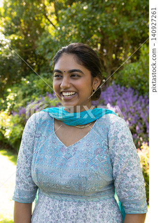 Indian woman standing in garden showcasing turquoise dupatta, bindi and nose ring 140927261