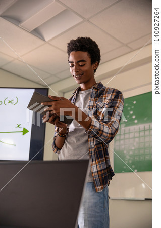 African American man presenting graph on screen in classroom while holding tablet and laptop African American man presenting graph on screen in classroom while holding tablet and laptop 140927264