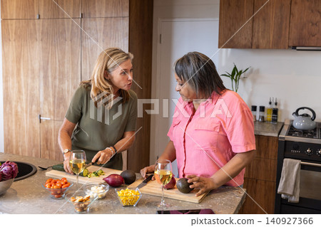 Diverse female friends chopping zucchini and avocado on granite kitchen island in kitchen 140927366