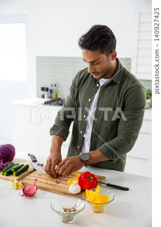 Man chopping cabbage with chef's knife on wooden cutting board at kitchen island, copy space Man chopping cabbage with chef's knife on wooden cutting board at kitchen island, copy space 140927425