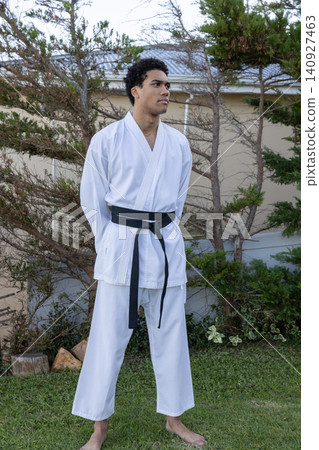 African american man standing barefoot on grassy lawn gazing left wearing karate gi with belt African american man standing barefoot on grassy lawn gazing left wearing karate gi with belt 140927463