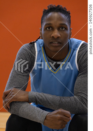 African american man crouching at court wearing blue basketball jersey over grey compression shirt African american man crouching at court wearing blue basketball jersey over grey compression shirt 140927506