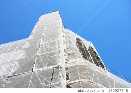 Urban Construction Scene with Building Facade Covered in Scaffolding and Protective Netting Urban Construction Scene with Building Facade Covered in Scaffolding and Protective Netting 140927546