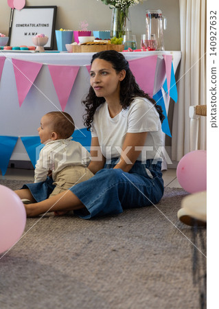 Mother with baby boy sitting on gray rug celebrating at home with marquee sign and balloons Mother with baby boy sitting on gray rug celebrating at home with marquee sign and balloons 140927632