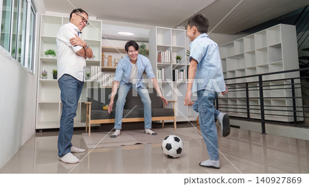 Multigenerational Asian family playing soccer together in living room Multigenerational Asian family playing soccer together in living room 140927869