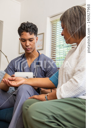 Senior patient sitting on sofa at home receiving blood pressure cuff check by asian male medical Senior patient sitting on sofa at home receiving blood pressure cuff check by asian male medical 140927968