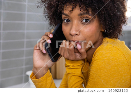 Woman leaning over kitchen countertop by backsplash while holding smartphone near wooden canisters Woman leaning over kitchen countertop by backsplash while holding smartphone near wooden canisters 140928133