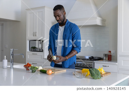 African american man in thirties slicing onion with chef knife on cutting board at kitchen African american man in thirties slicing onion with chef knife on cutting board at kitchen 140928145