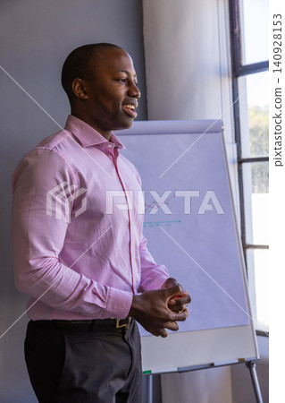 African american man explaining line graph on flip chart in office, copy space 140928153
