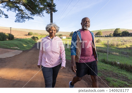 African american senior couple walking on dirt road past wire fence and pasture African american senior couple walking on dirt road past wire fence and pasture 140928177