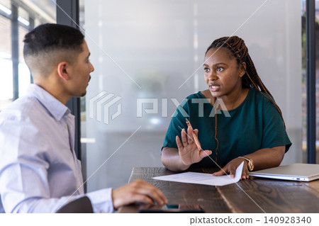 Coworkers reviewing report in office, woman using pen with laptop, smartphone, copy space 140928340
