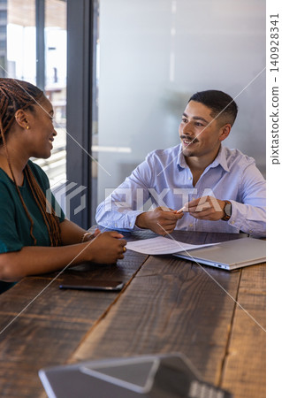 Diverse coworkers discussing documents in conference room with laptop 140928341