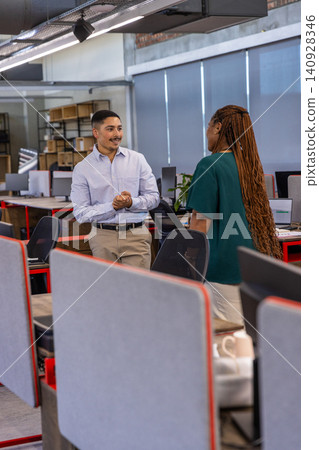 Diverse coworkers collaborating on project in open-plan office near swivel chairs, monitors Diverse coworkers collaborating on project in open-plan office near swivel chairs, monitors 140928346