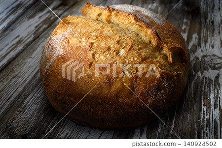 Freshly baked artisanal bread resting on rustic wooden table warm golden crust Freshly baked artisanal bread resting on rustic wooden table warm golden crust 140928502