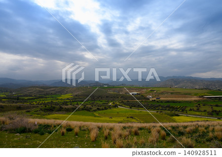 Rolling hills adorned with vibrant greens and dramatic skies in an enchanting countryside landscape Rolling hills adorned with vibrant greens and dramatic skies in an enchanting countryside landscape 140928511