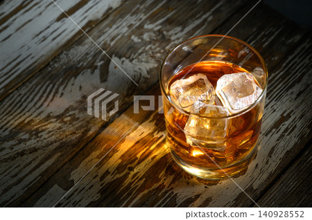 Perfectly chilled drink resting on rustic wooden table illuminated by soft light 140928552