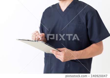 A middle-aged male doctor in navy blue scrubs holding a binder of patient questionnaires. 140928847