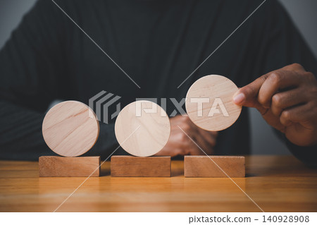 Closeup of a man hand in a pose showing a meaningful sign and gesture for a business concept, placing a wooden circle as a sign for planning strategy and development Closeup of a man hand in a pose showing a meaningful sign and gesture for a business concept, placing a wooden circle as a sign for planning strategy and development 140928908