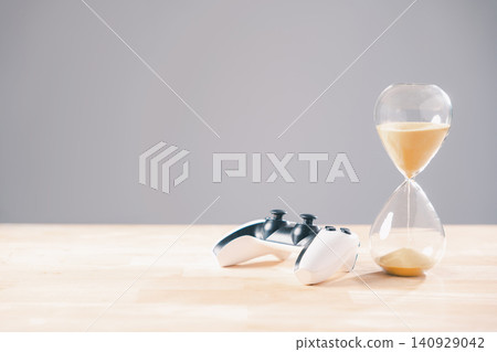 Gaming controller, hourglass with golden sand falling, visually represents crucial time management concept for gamer, showing importance of limiting video game play duration Gaming controller, hourglass with golden sand falling, visually represents crucial time management concept for gamer, showing importance of limiting video game play duration 140929042