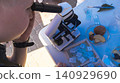 Curious boy looking through a microscope at an outdoor science fair. Enthusiastic kid exploring biology sample during an educational laboratory festival. Curious boy looking through a microscope at an outdoor science fair. Enthusiastic kid exploring biology sample during an educational laboratory festival. 140929690