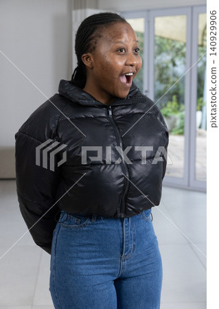 African American adult woman looking surprised at home wearing black jacket, jeans, braided hair African American adult woman looking surprised at home wearing black jacket, jeans, braided hair 140929906