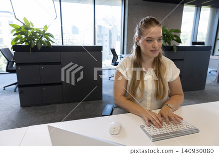 Female office worker in white blouse typing on wireless keyboard with mouse at desk, copy space Female office worker in white blouse typing on wireless keyboard with mouse at desk, copy space 140930080