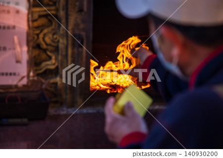 A close-up of the traditional Taiwanese temple ritual of burning joss paper and devout believers. A close-up of the traditional Taiwanese temple ritual of burning joss paper and devout believers. 140930200