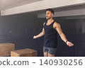 Man skipping rope beside two wooden plyometric boxes in gym wearing fitness watch, copy space 140930256
