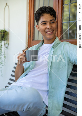 Man sitting on covered porch slatted bench holding ceramic coffee mug, looking toward garden Man sitting on covered porch slatted bench holding ceramic coffee mug, looking toward garden 140930306