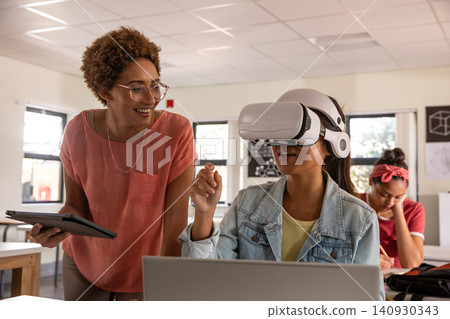 African American teacher guiding student in VR at classroom desk with tablet, copy space African American teacher guiding student in VR at classroom desk with tablet, copy space 140930343
