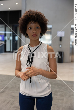 African american woman standing at elevator call panel in office lobby in white top dark pants African american woman standing at elevator call panel in office lobby in white top dark pants 140930441