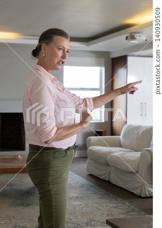 Woman pointing finger while presenting slideshow with projector and sofa in living room Woman pointing finger while presenting slideshow with projector and sofa in living room 140930509