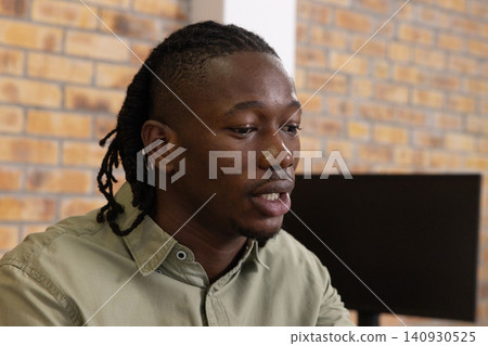 African american man wearing button-down shirt working at desk with monitor in office, copy space African american man wearing button-down shirt working at desk with monitor in office, copy space 140930525