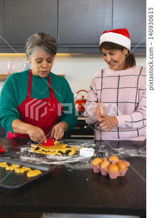 African American mother and daughter baking cookies wearing Santa hat at flour-dusted counter African American mother and daughter baking cookies wearing Santa hat at flour-dusted counter 140930615