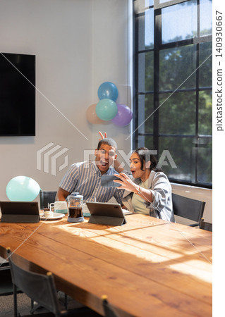Diverse coworkers sitting at office conference table taking selfie, smartphone under balloons Diverse coworkers sitting at office conference table taking selfie, smartphone under balloons 140930667