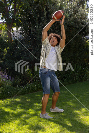 Man catching american football on backyard grass lawn Man catching american football on backyard grass lawn 140930880