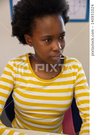 African american teenage girl studying at white desk in classroom with whiteboard and chair African american teenage girl studying at white desk in classroom with whiteboard and chair 140931024