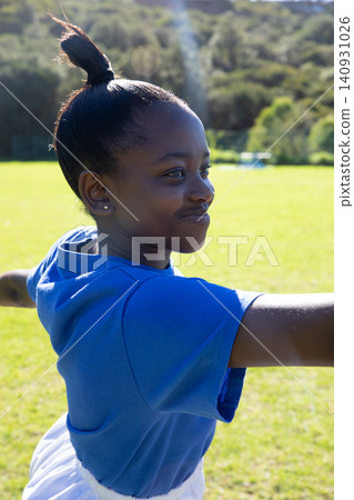 African american girl stretching arms wide wearing sportswear on grassy field African american girl stretching arms wide wearing sportswear on grassy field 140931026