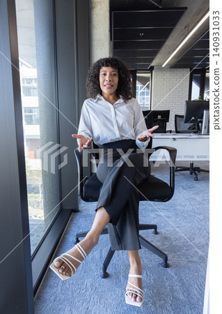 African american woman wearing work attire sitting at desk using keyboard with monitors 140931033
