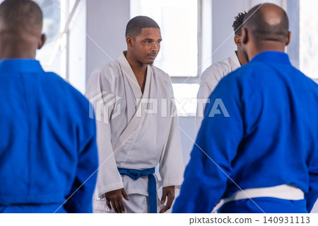 Diverse male training partners practicing martial arts moves in dojo on cushioned mats 140931113